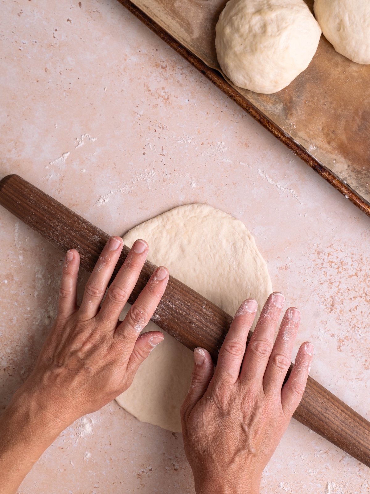 Using a rolling pin to roll out sourdough naan dough
