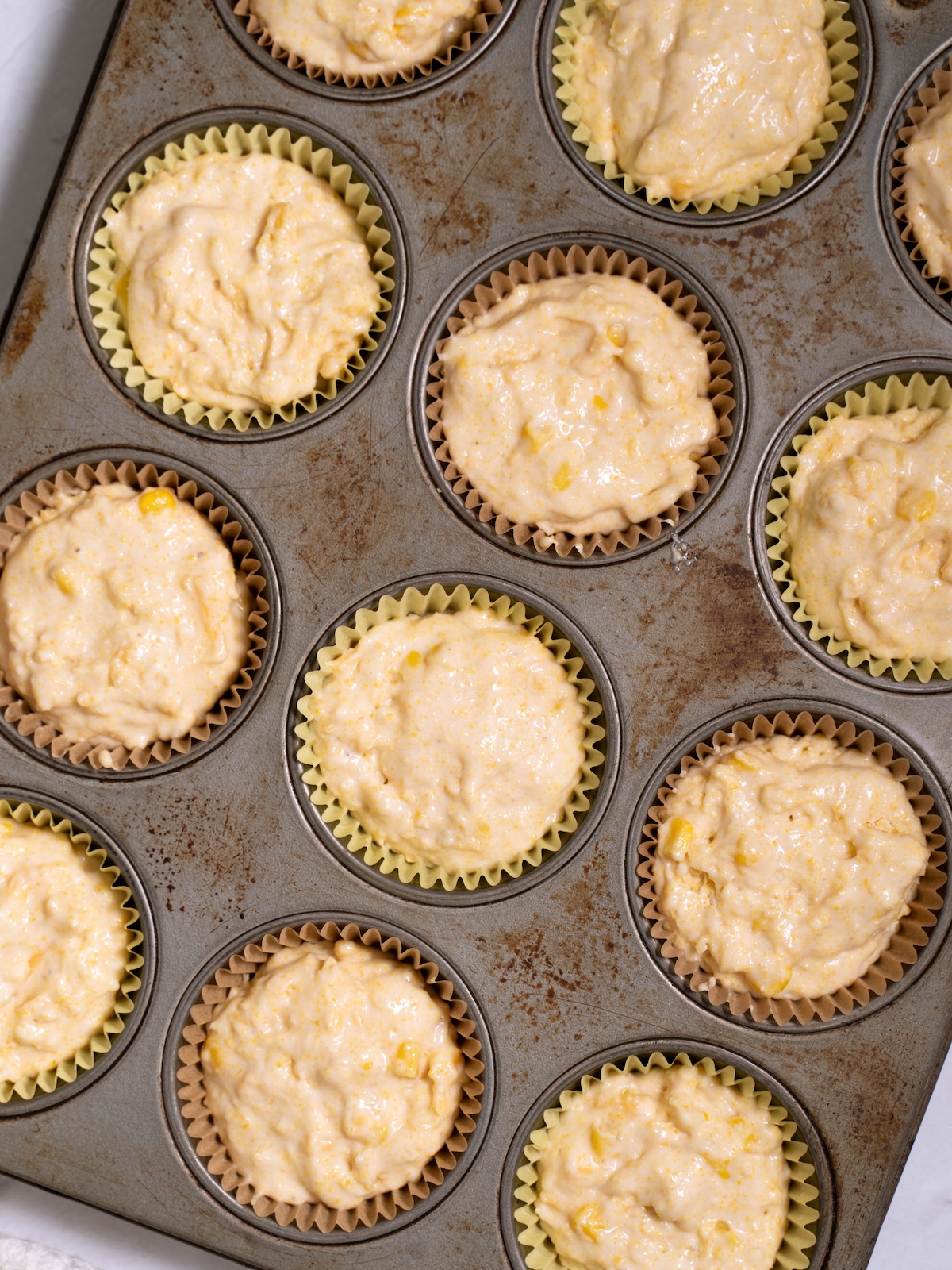 Corn muffin batter scooped into a muffin tin
