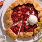 A strawberry fennel pollen galette on a serving plate, with fresh fennel flowers