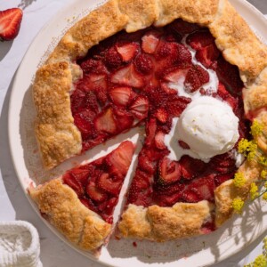 A strawberry fennel pollen galette on a serving plate, with fresh fennel flowers