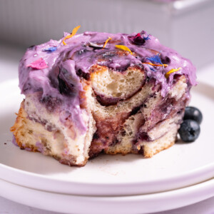 A blueberry cinnamon roll on a plate with a bite taken out of it