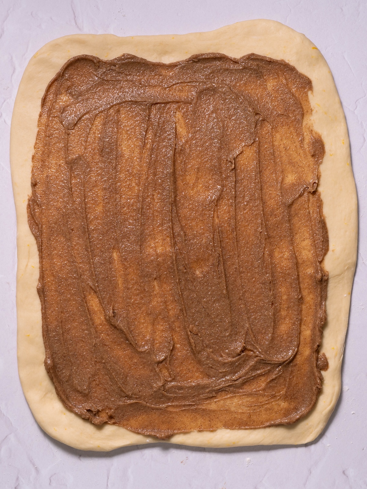 Cinnamon butter spread onto cinnamon roll dough