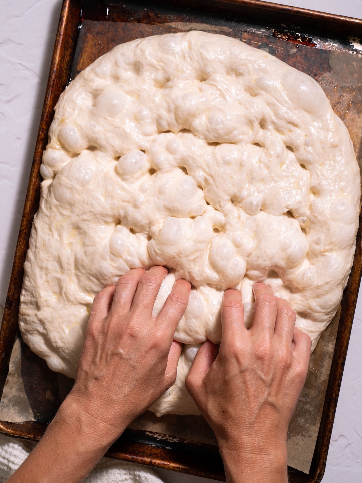 Dimpling bubbly focaccia dough with fingers