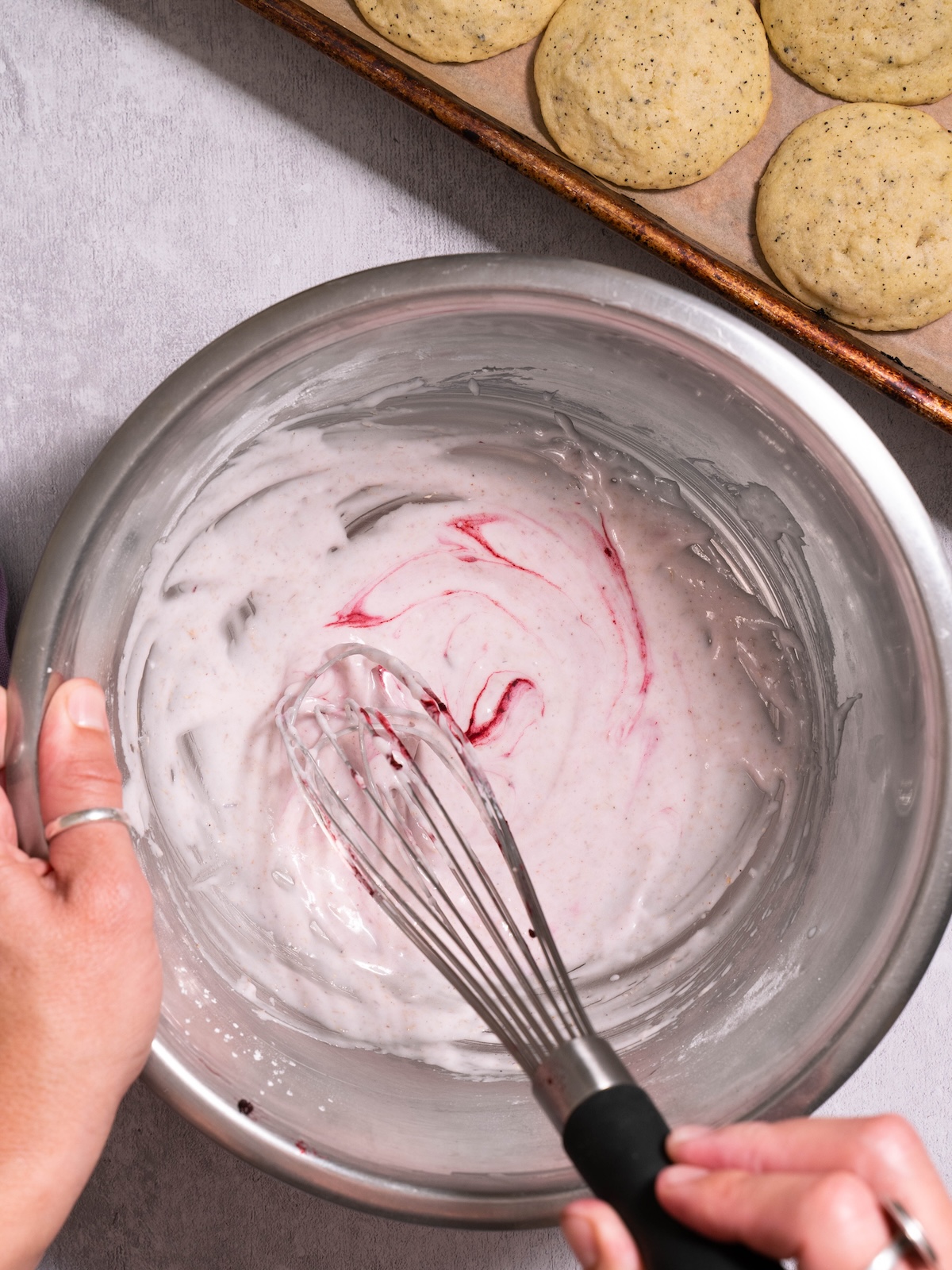 Swirling blackberry juice into powdered sugar glaze to turn it light purple