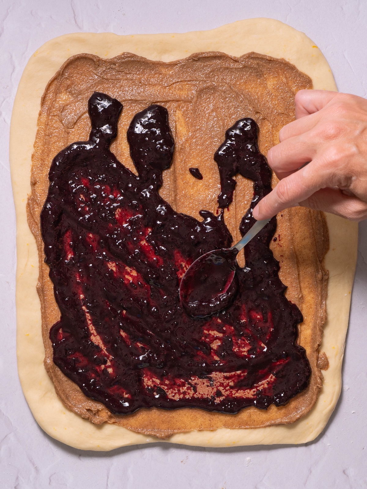 Spreading blueberry jam on top of cinnamon butter