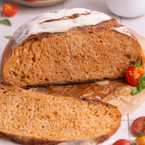 A loaf of roasted tomato basil sourdough bread, sliced open
