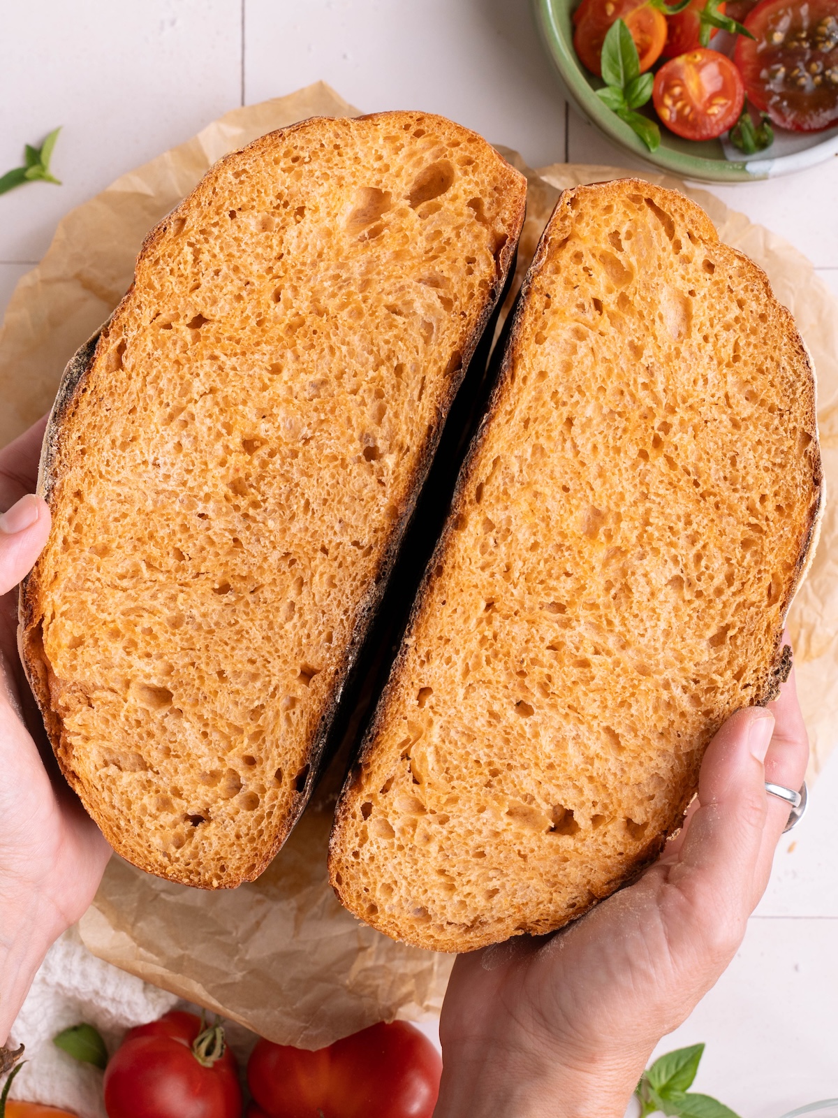 Roasted tomato basil sourdough bread, split in half to show beautiful color inside