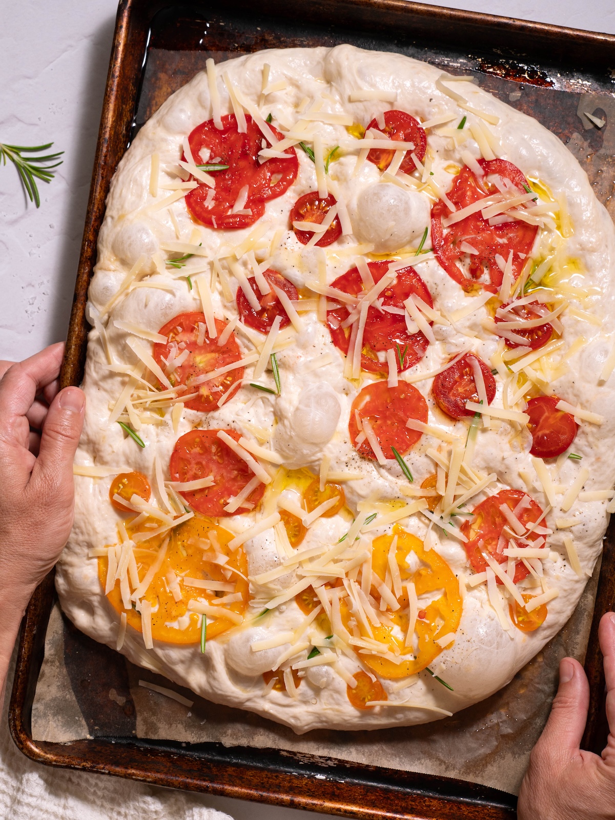 Focaccia dough topped with tomatoes, rosemary, and parmesan
