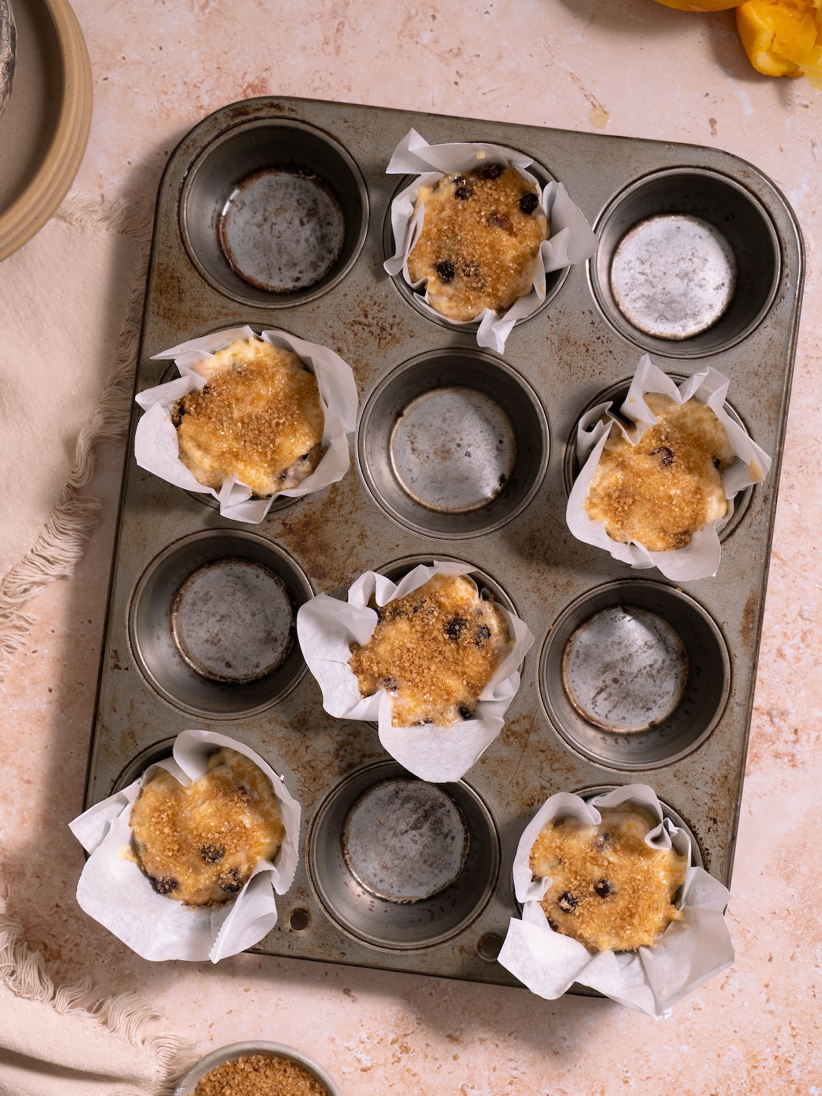 Muffin batter, topped with coarse sugar, in muffin tins before baking