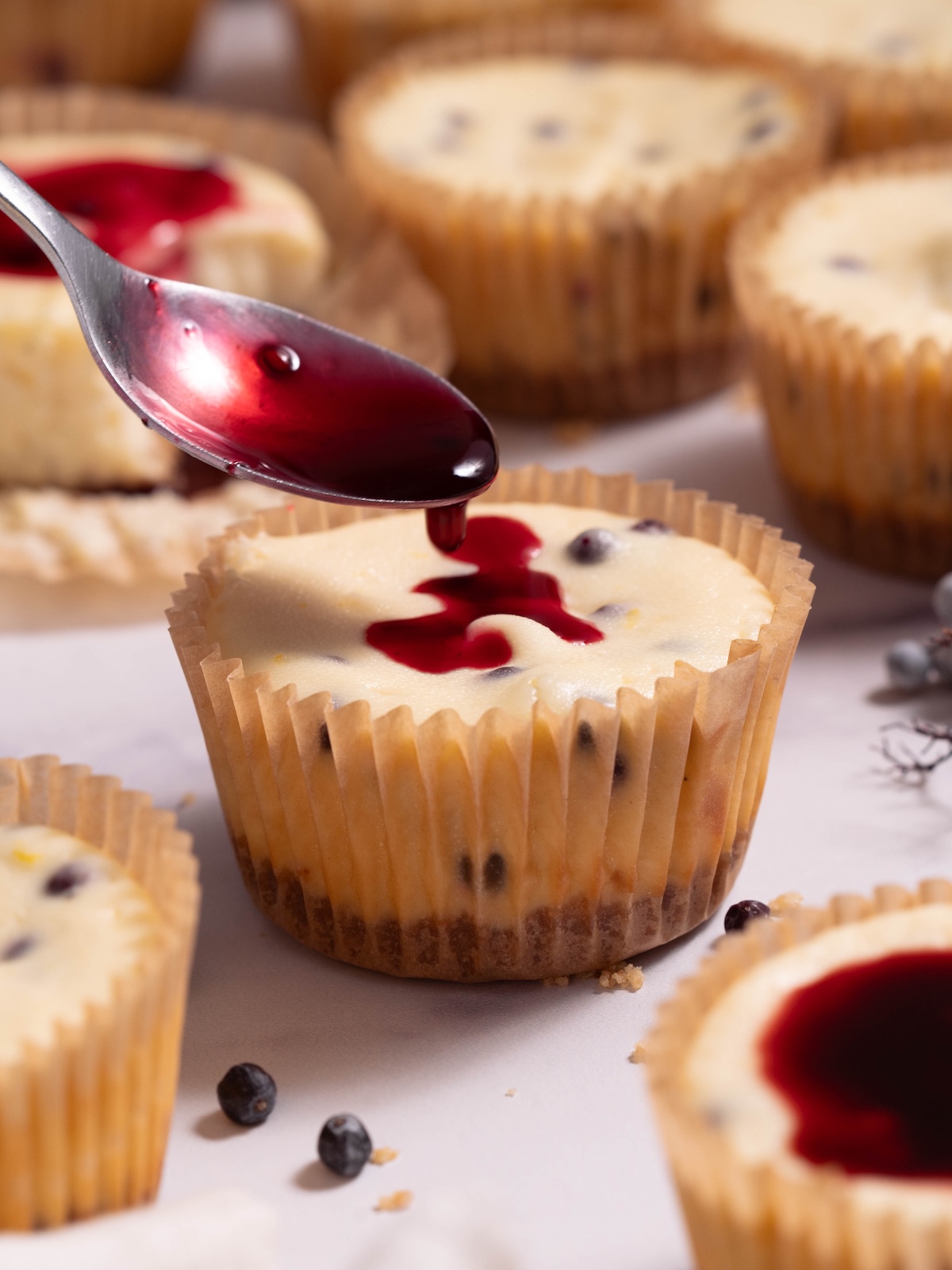 Spooning elderberry sauce onto a miniature cheesecake