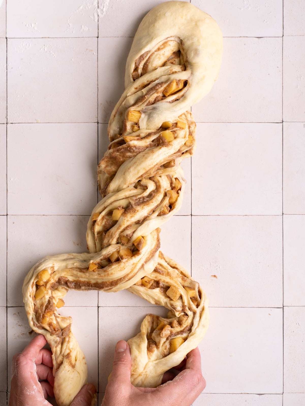 Hands twisting a cinnamon apple breakfast twist