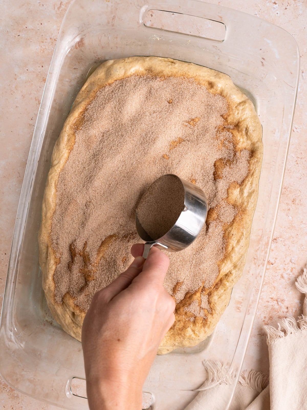 Sprinkling cinnamon sugar on focaccia dough