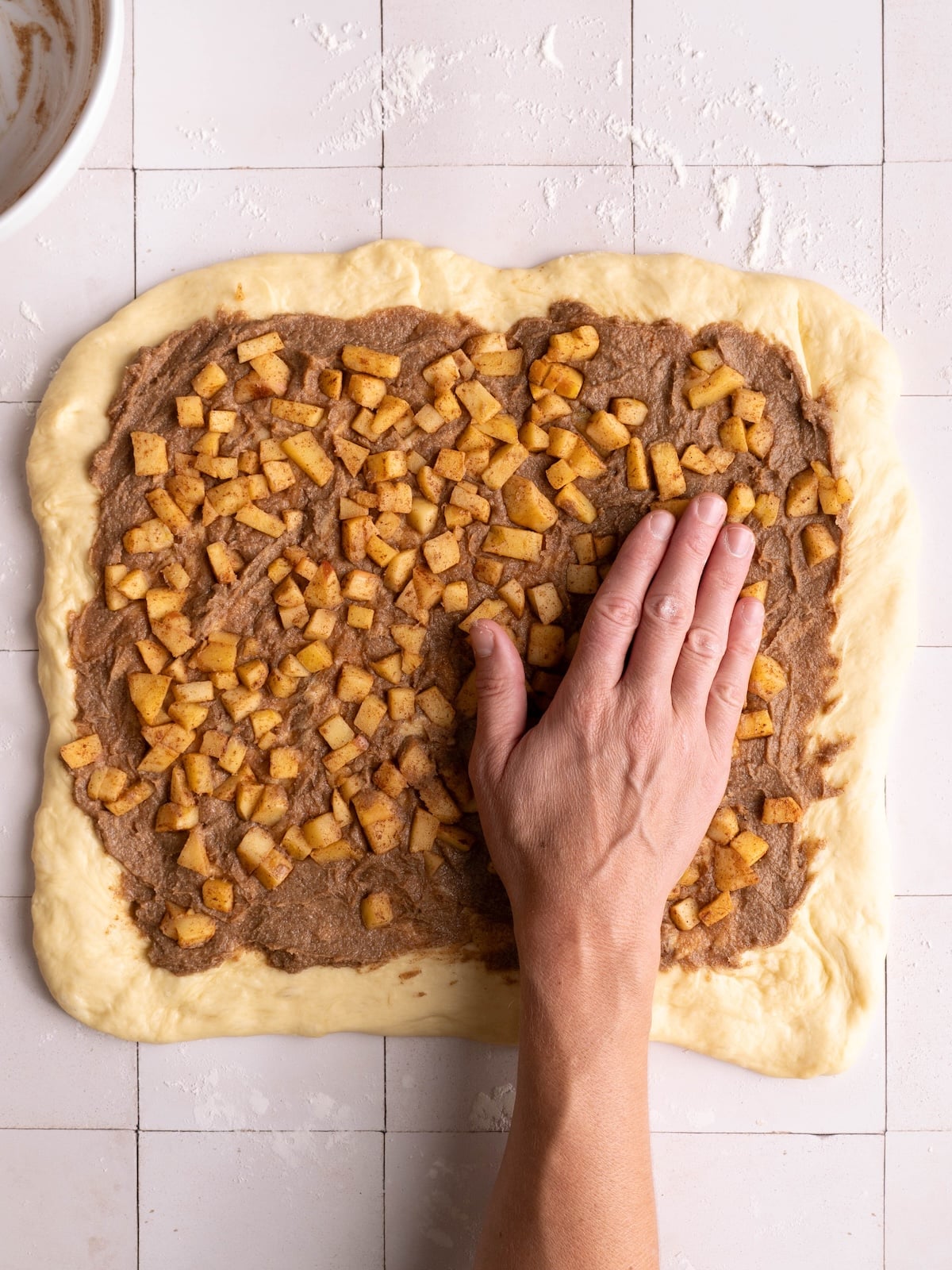 Pressing apples into cinnamon butter on sweet roll dough
