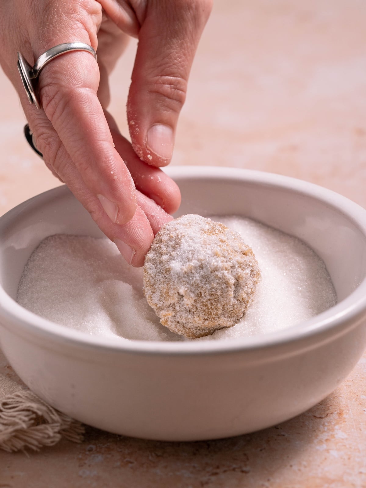 Rolling molasses cookie dough in sugar before baking